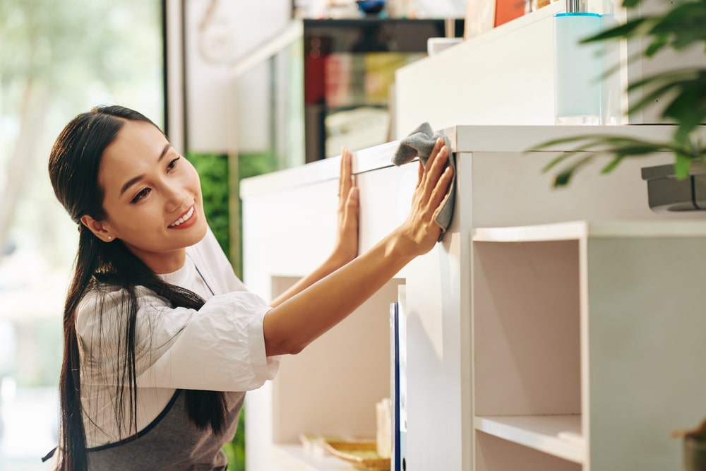 Smiling woman cleaning hard surface with Clean Habits products
